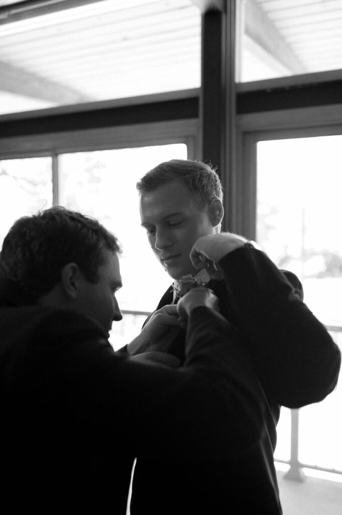 groom putting on jacket by Illinois wedding photographer