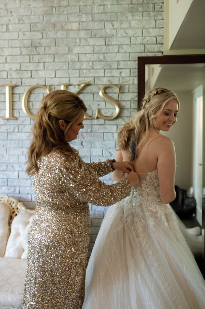 mother of bride buttoning wedding dress by Illinois wedding photographer