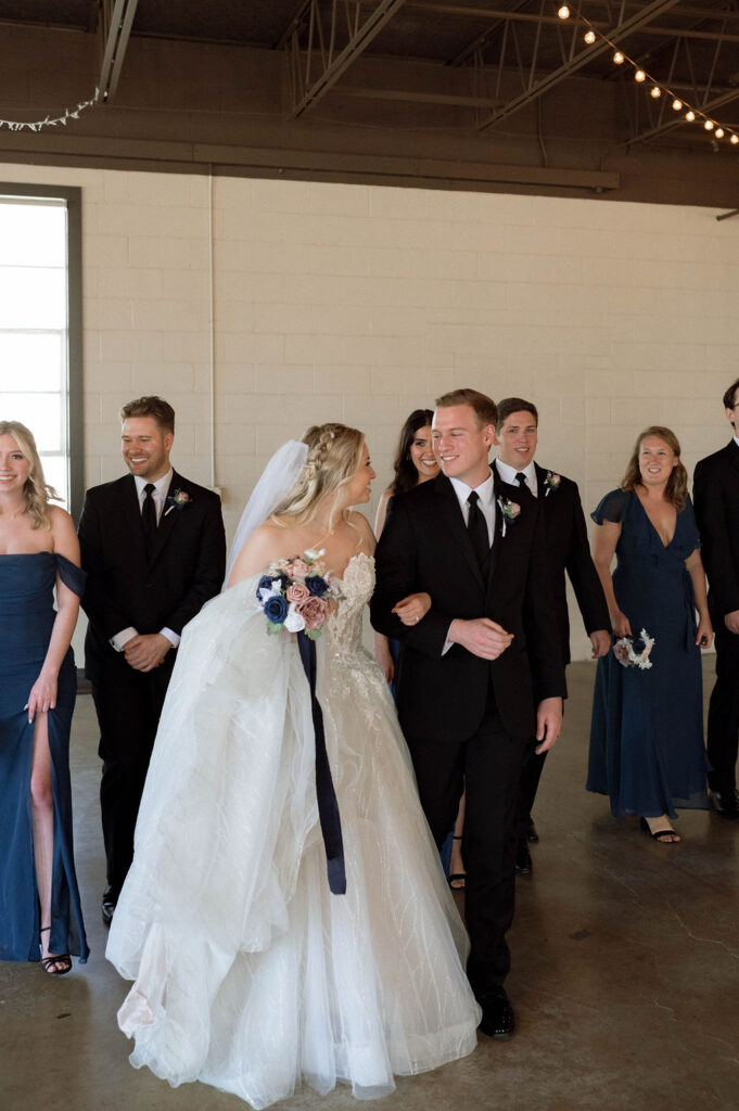 bride & groom walking with wedding party by Illinois wedding photographer