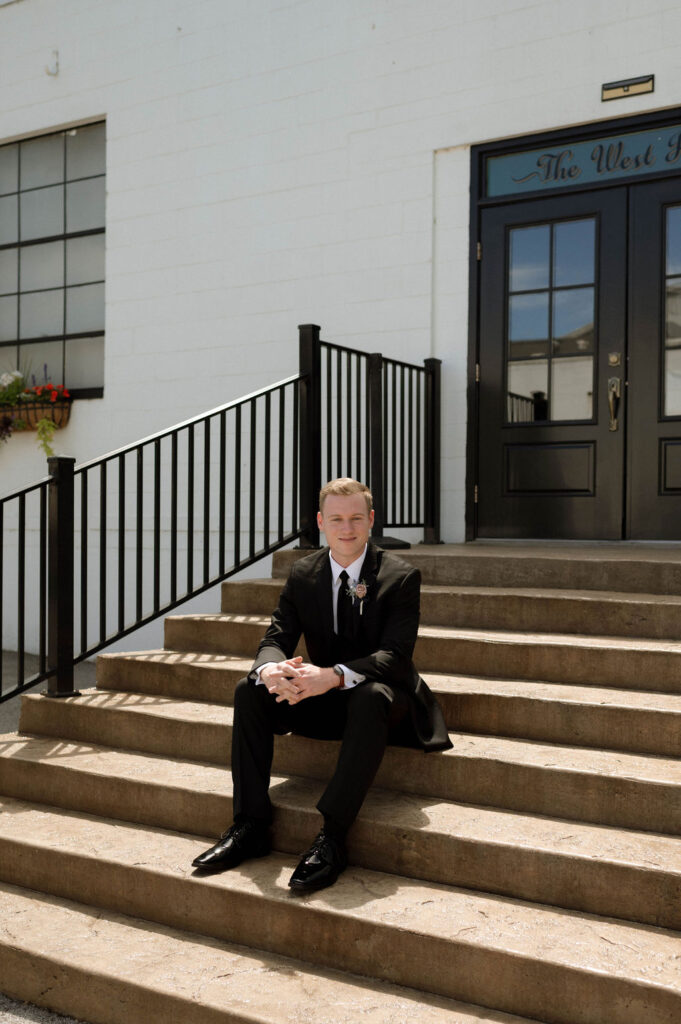 groom sitting on the steps by DFW Wedding Photographer 