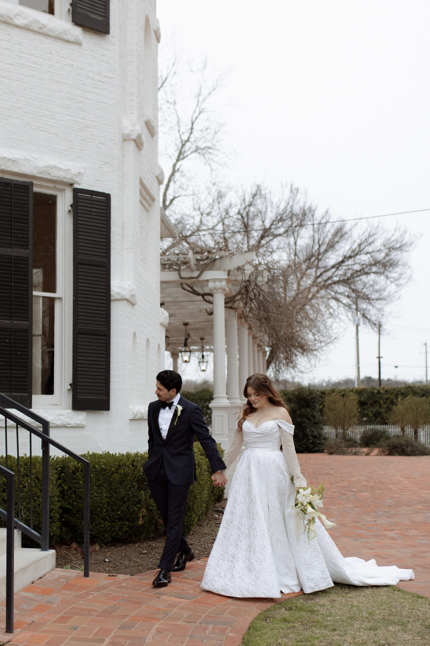 Photo of Bride and groom walking outside of Woodbine Mansion during their winter wedding in Austin, TX