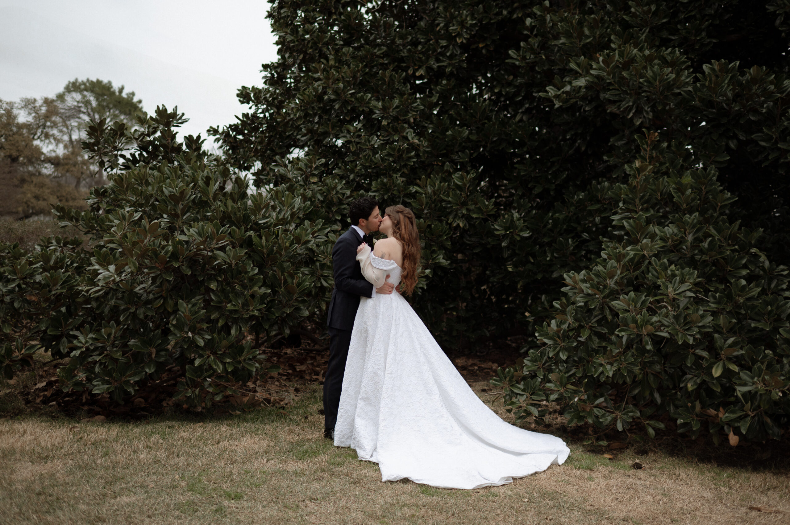 bride and groom kissing in front of the magnolia tree at Woodbine Mansion, the best wedding venue in Texas
