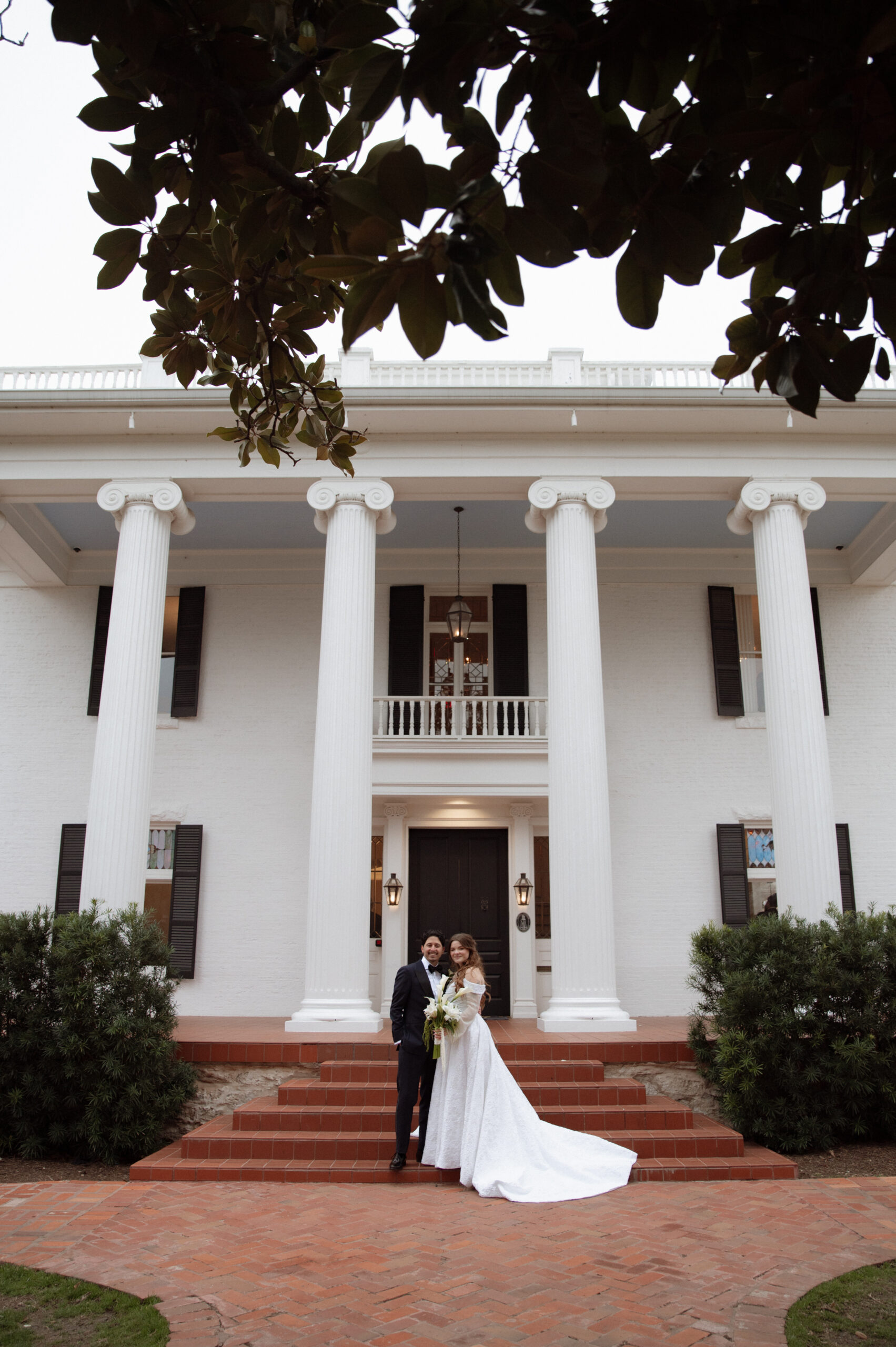 Bride and groom standing together for a photo in front of the best Austin Wedding venue, Woodbine Mansion taken by Nicole Endress Photography