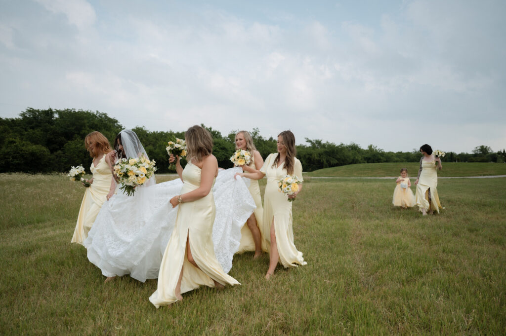 bride and bridesmaids walking in a field of grass at Hawthorne Hills Ranch in Krum, TX