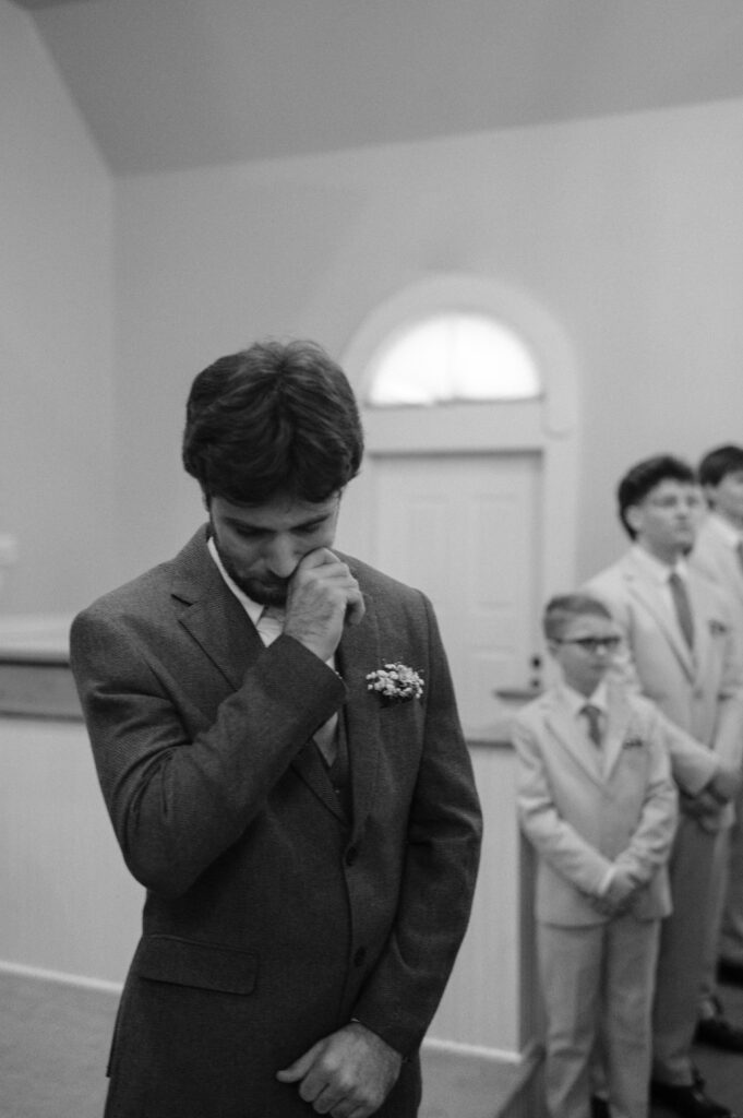 groom crying at the altar as he watches his bride walk down the aisle.