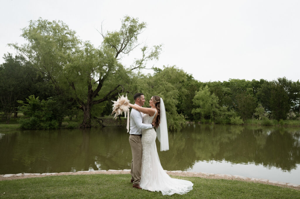 bride and groom looking at each other in front of the water at their Dallas wedding