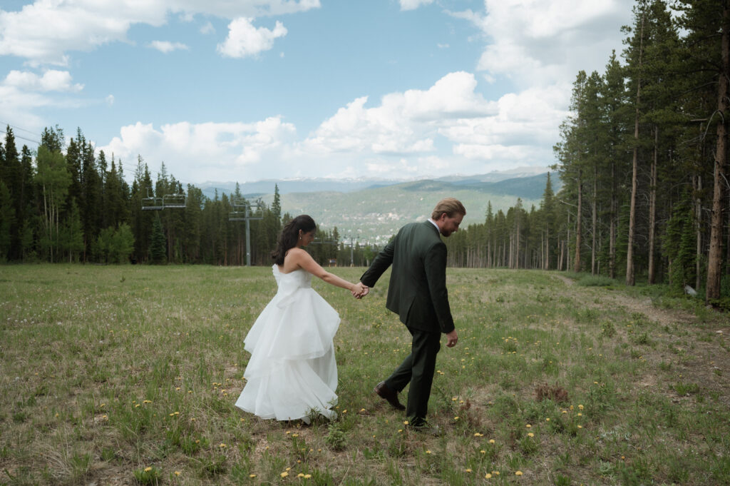 bride and groom walking with the mountains in the background at their wedding at TenMile Station in Breckenridge, CO
