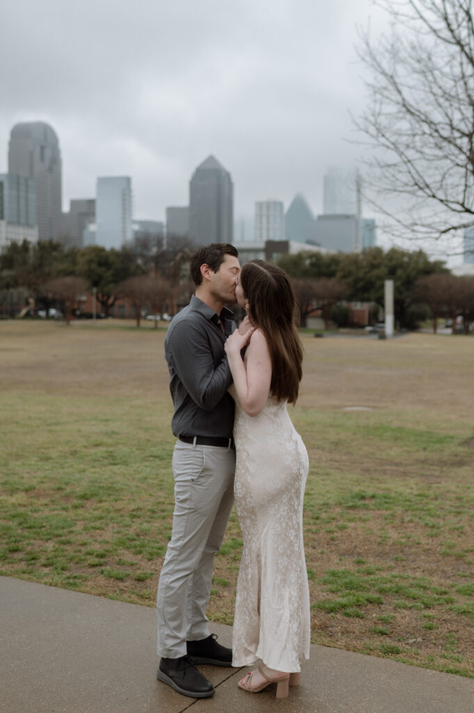 engagement photo of couple kissing in front of Dallas Skyline
