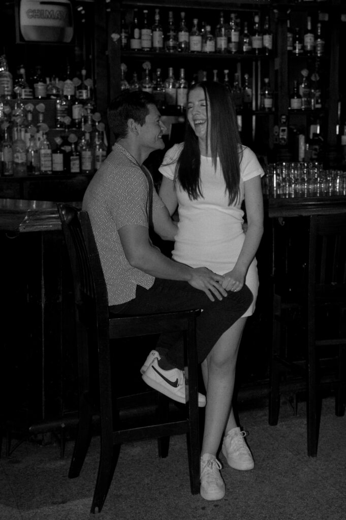 engaged couple laughing side a bar