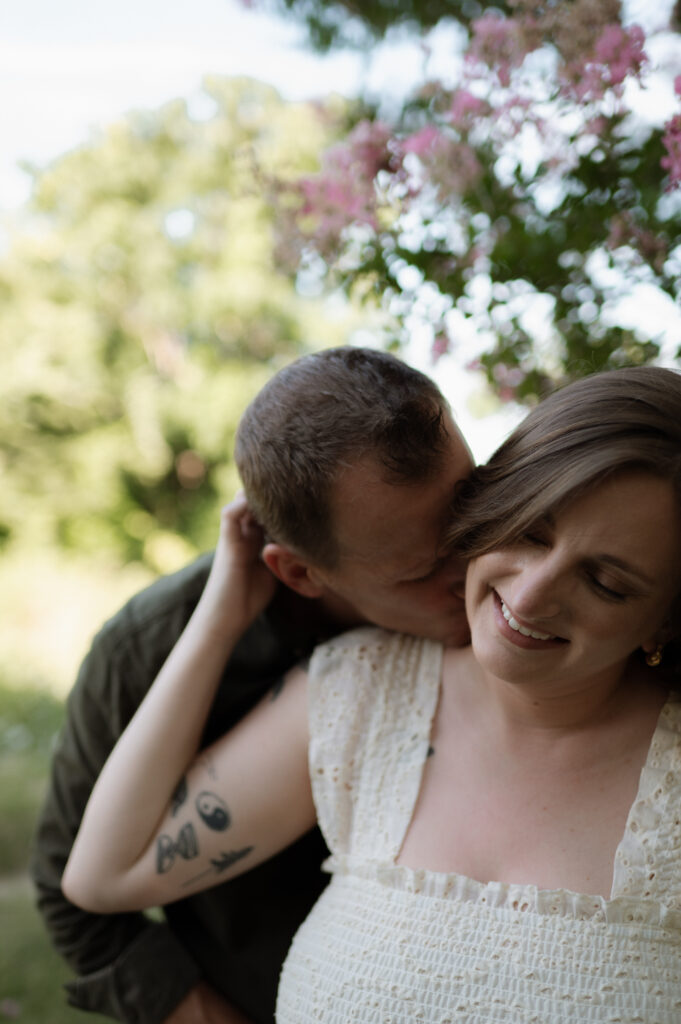 couple kissing neck for engagement photos