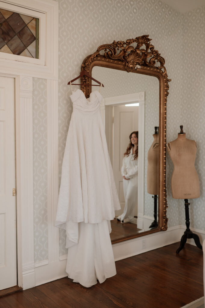 bride looking at her wedding dress hanging on a mirror taken by Austin Wedding Photographer