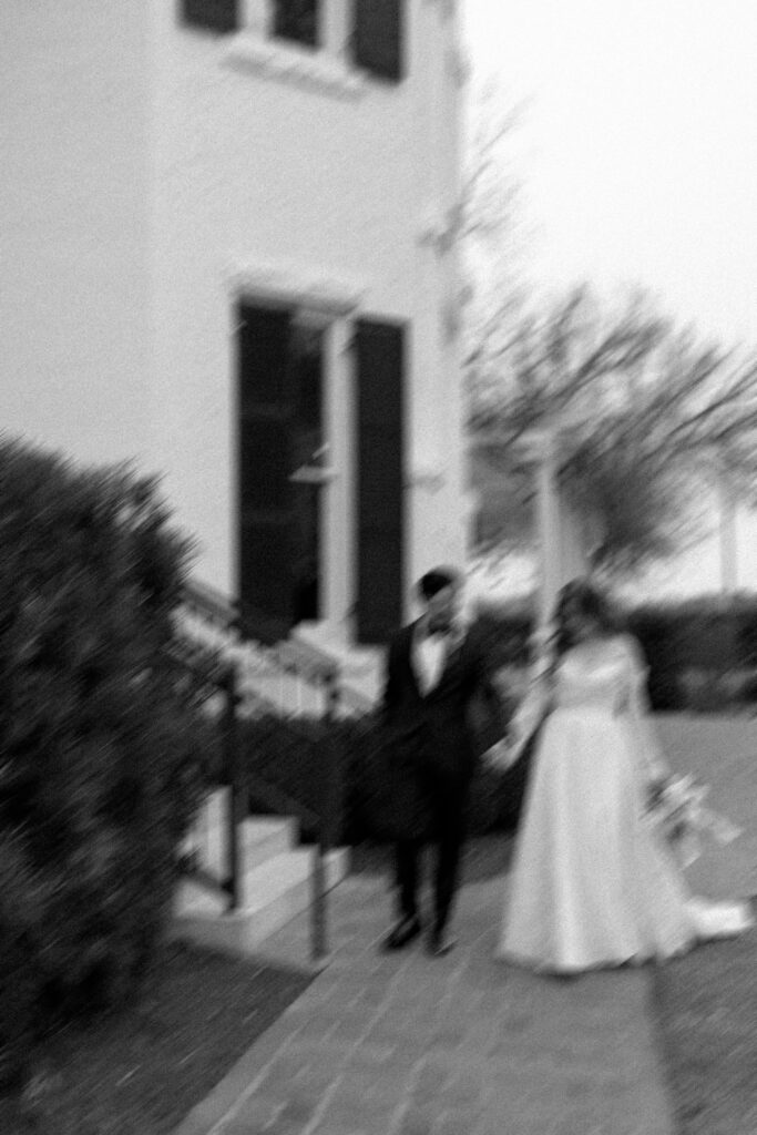 motion blur black and white photo of bride and groom walking