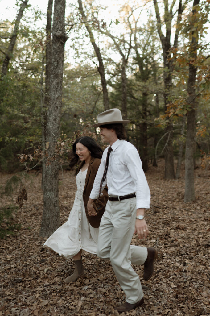 romantic couple running through a forest together