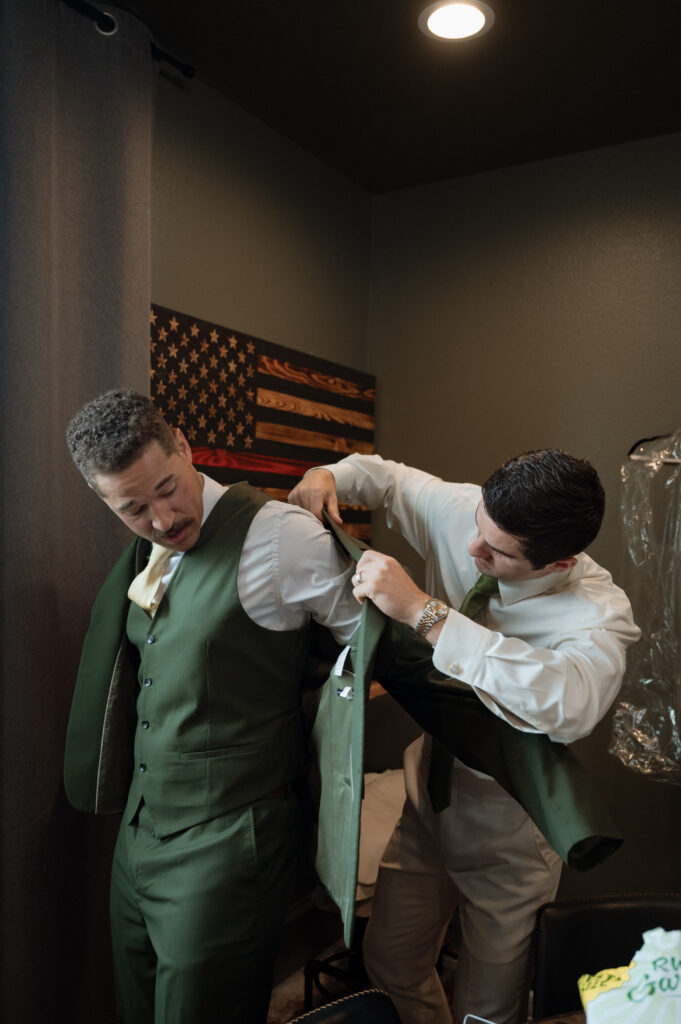 best man helping groom put on his jacket
