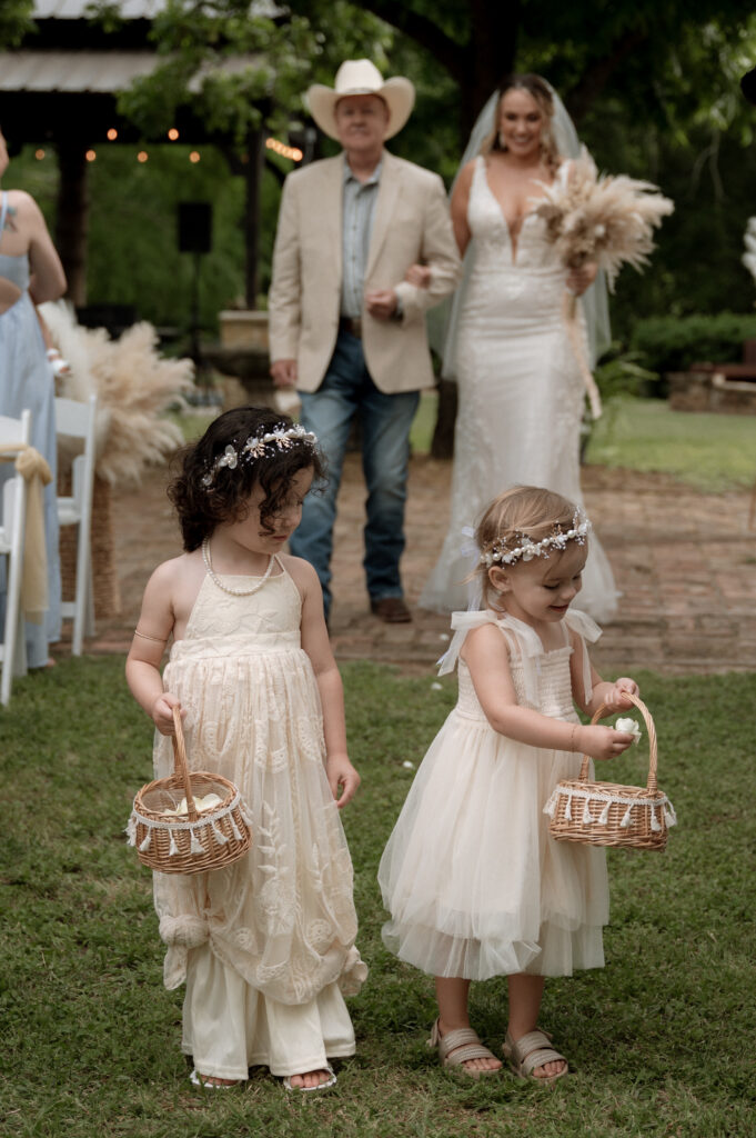 photo of bride walking down the aisle with flower girls in front of her