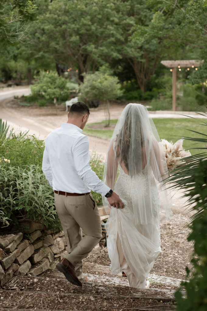 groom carrying bride's dress down the steps