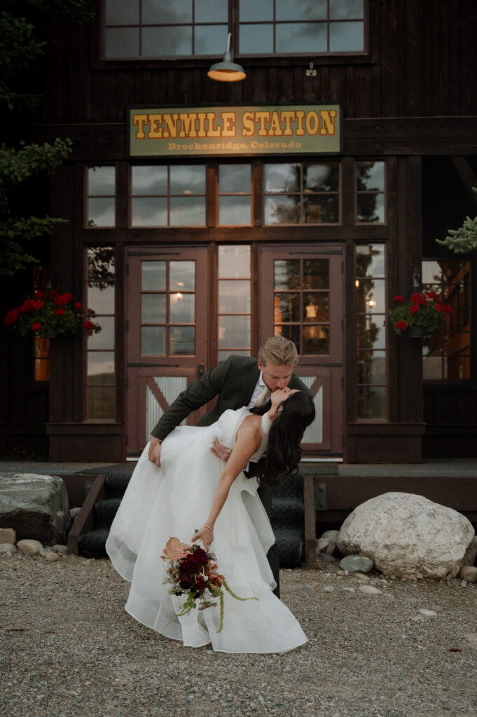 Bride and groom kissing in front of TenMile Station taken by Breckenridge Wedding Photographer