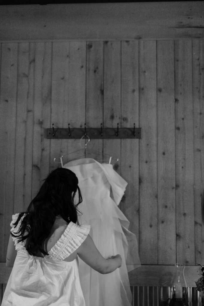 Bride looking at her wedding dress hanging taken by Nicole Endress Photography