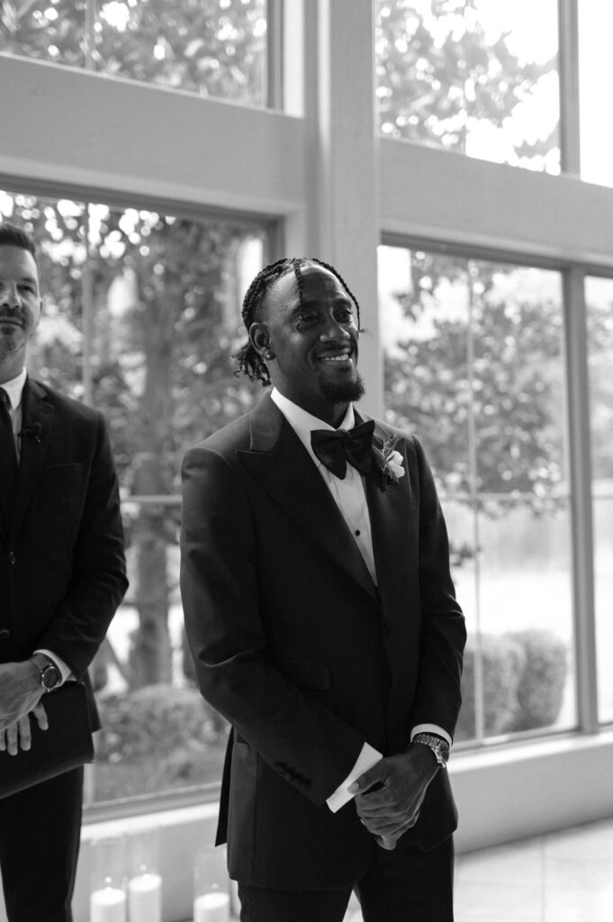 photo of groom watching his bride walk down the aisle 
