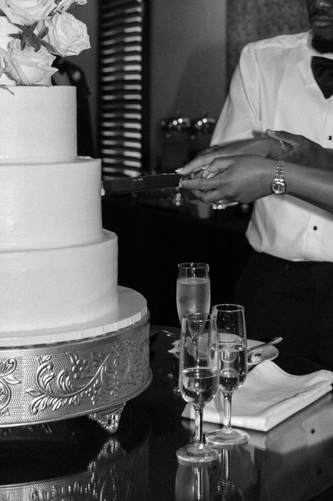 closeup photo of bride and groom cutting wedding cake
