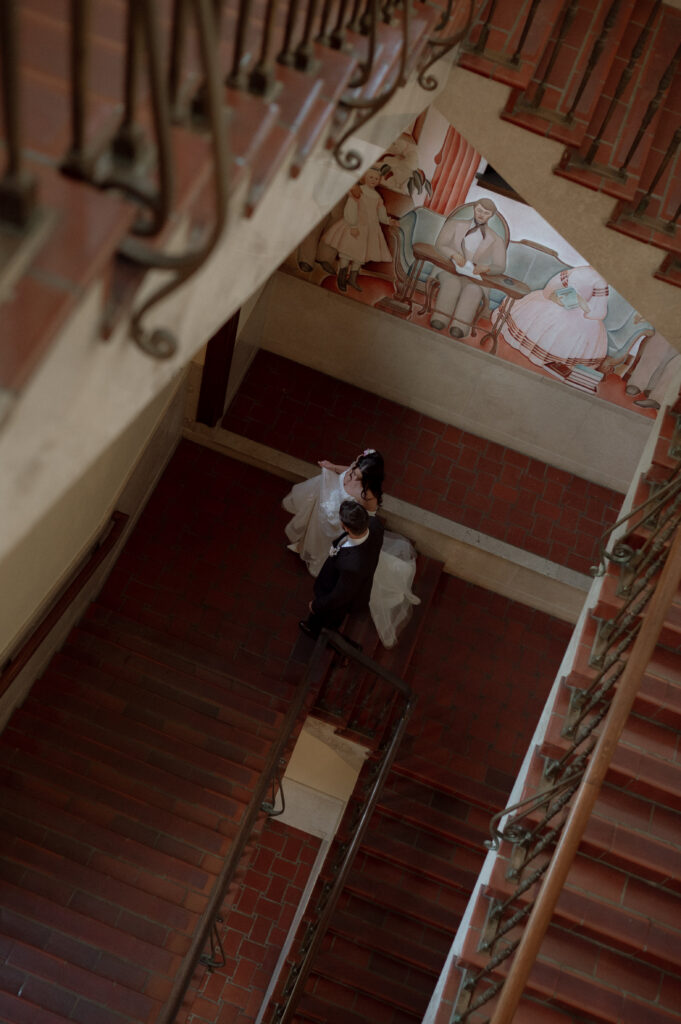 whimsical wedding photo of bride and groom walking upstairs taken by Nicole Endress Photography