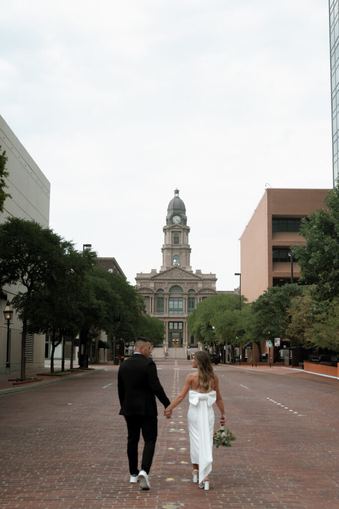 bride and groom walking towards the Tarrant County Courthouse in Fort Worth, TX